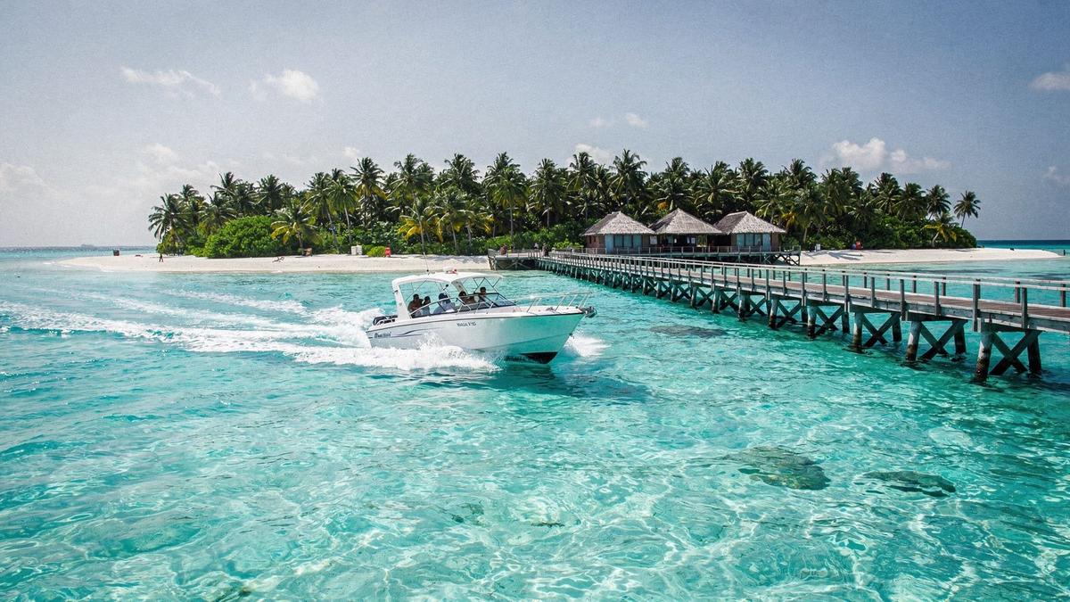 Speedboat crossing to a resort jetty on a turquoise atoll in the Maldives